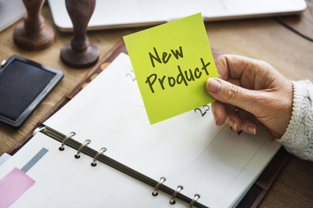 caderno em mesa executiva com nota com a frase new product