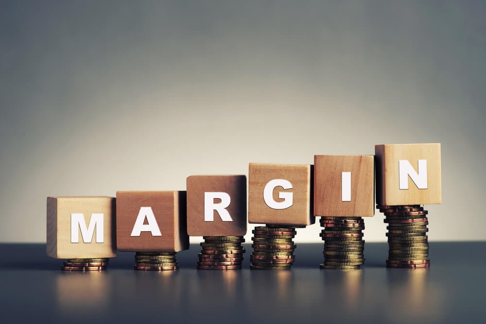 cubos com letras montando palavra Margem em inglês acima de moedas