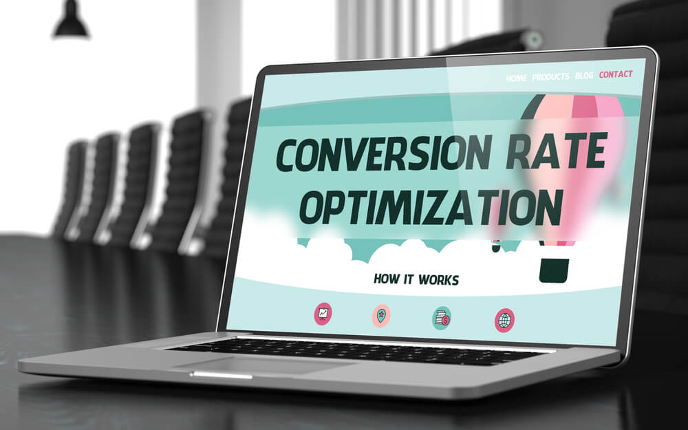 laptop sob mesa com palavra conversion rate optimization em tela