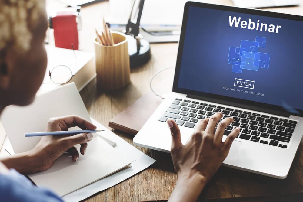 laptop sob mesa e acesso á página de Webinar