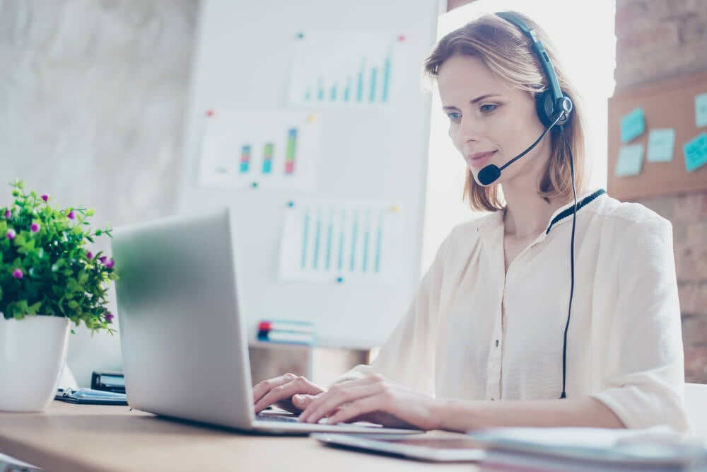 mulher trabalhando em laptop com fone de ouvido e gráficos de resultados